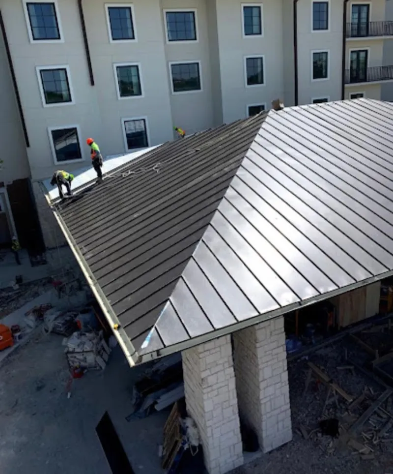 Crew installing standing seam metal roof panels on a commercial project in Brunswick